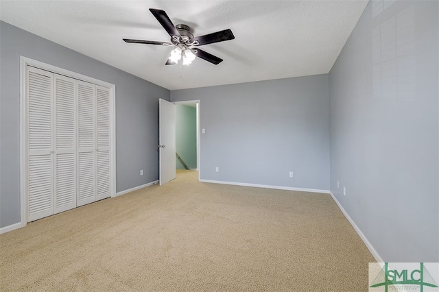 unfurnished bedroom featuring light carpet, a closet, ceiling fan, and a textured ceiling