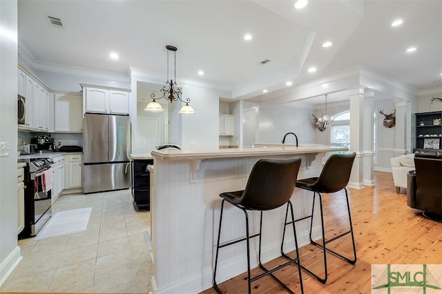 kitchen with white cabinets, appliances with stainless steel finishes, a breakfast bar area, open floor plan, and a kitchen island with sink