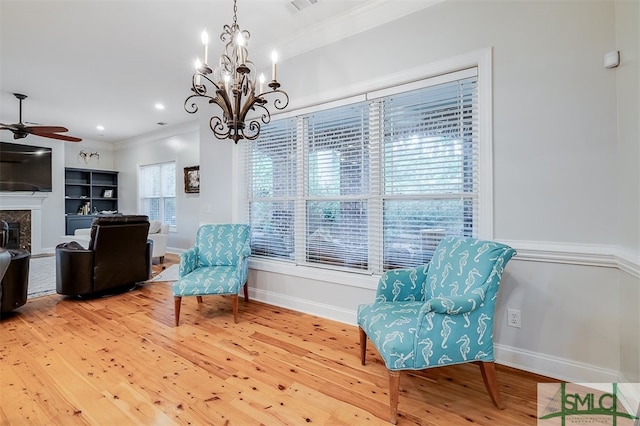 sitting room featuring baseboards, ceiling fan, wood finished floors, crown molding, and a high end fireplace