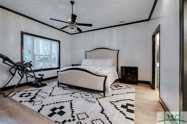 bedroom with baseboards, visible vents, crown molding, and light wood finished floors