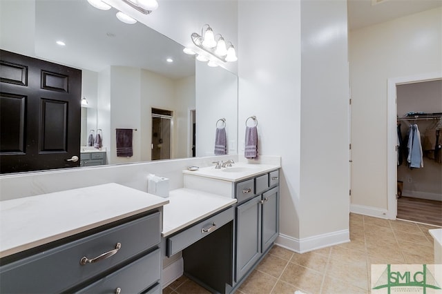 full bathroom featuring baseboards, tile patterned flooring, a walk in closet, vanity, and a shower stall