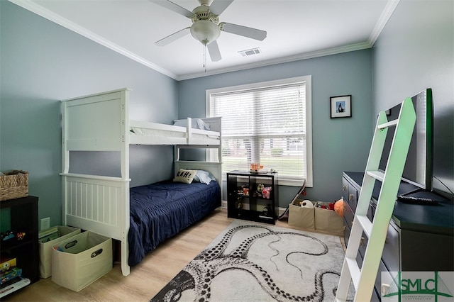 bedroom featuring light wood-style floors, a ceiling fan, visible vents, and crown molding