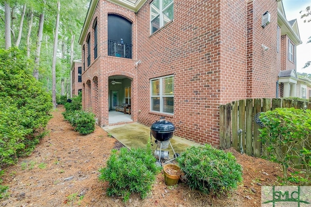 view of side of home featuring brick siding, a patio area, and fence