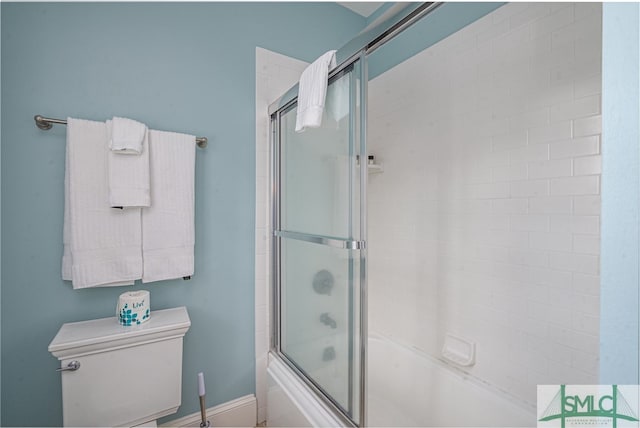 bathroom featuring bath / shower combo with glass door and toilet