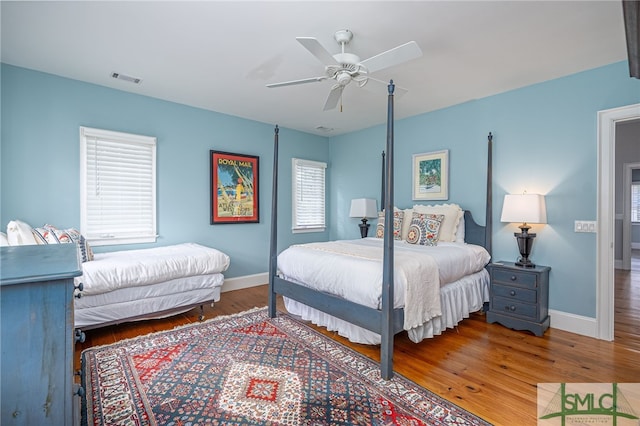 bedroom with multiple windows, ceiling fan, and hardwood / wood-style flooring