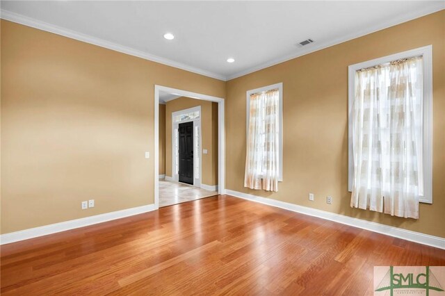 spare room featuring ornamental molding, light hardwood / wood-style floors, and a wealth of natural light