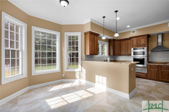 kitchen featuring stainless steel double oven, wall chimney exhaust hood, backsplash, decorative light fixtures, and ornamental molding