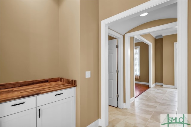 corridor with crown molding and light tile patterned floors