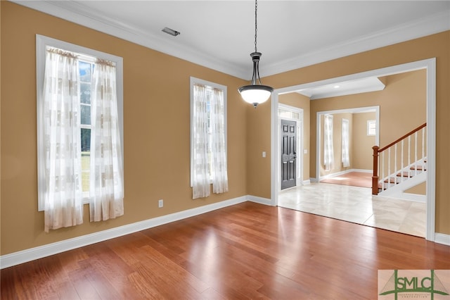 spare room with wood-type flooring, crown molding, and a wealth of natural light