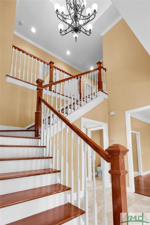 staircase with ornamental molding, a towering ceiling, and an inviting chandelier