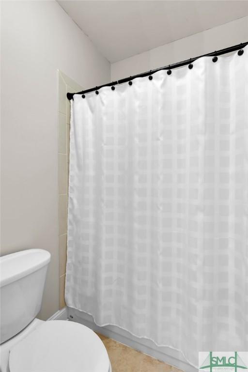 bathroom with toilet and a shower with shower curtain