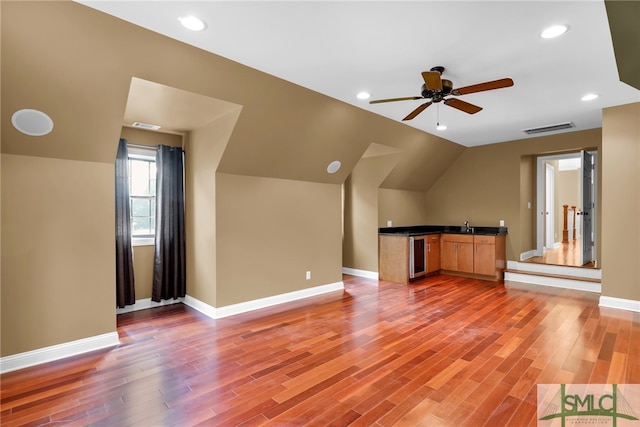 additional living space featuring ceiling fan, wine cooler, sink, wood-type flooring, and vaulted ceiling