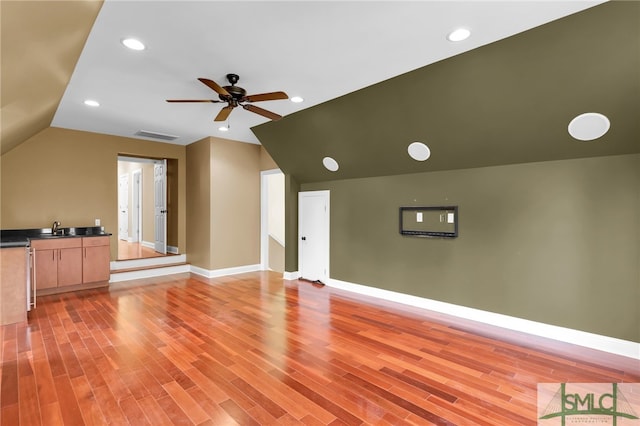 unfurnished living room with ceiling fan, light wood-type flooring, sink, and lofted ceiling