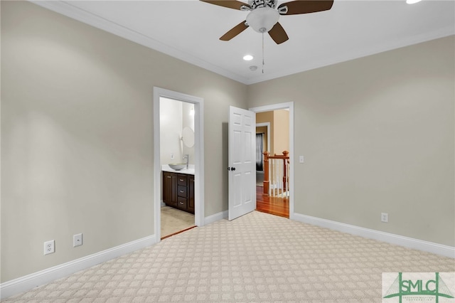 unfurnished bedroom featuring ceiling fan, sink, crown molding, light carpet, and ensuite bath