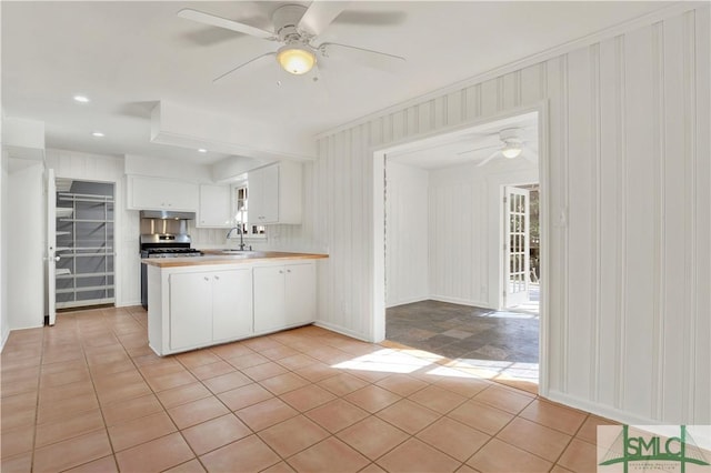 kitchen featuring sink, stainless steel stove, ceiling fan, white cabinets, and kitchen peninsula