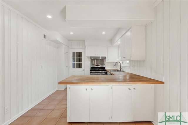 kitchen with sink, white cabinetry, stainless steel range oven, light tile patterned flooring, and kitchen peninsula