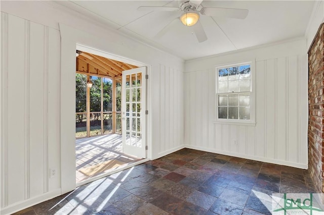 spare room featuring stone tile flooring, a healthy amount of sunlight, and ceiling fan