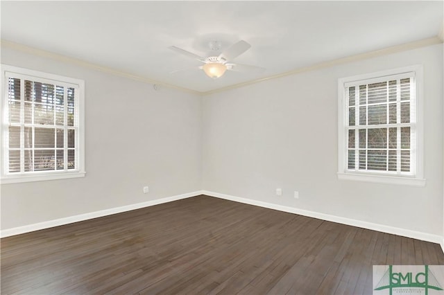 empty room with dark wood-style floors, crown molding, and baseboards