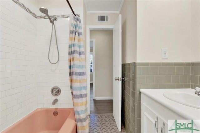 bathroom with crown molding, tile walls, visible vents, shower / bathtub combination with curtain, and vanity