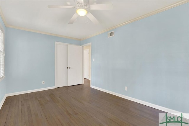 empty room featuring baseboards, visible vents, a ceiling fan, wood finished floors, and crown molding