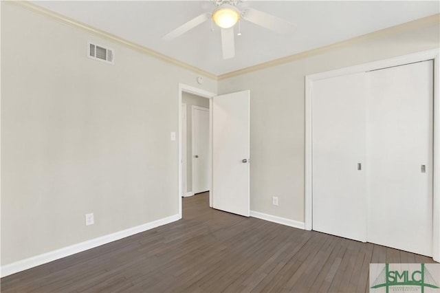 unfurnished bedroom featuring a closet, crown molding, dark hardwood / wood-style floors, and ceiling fan