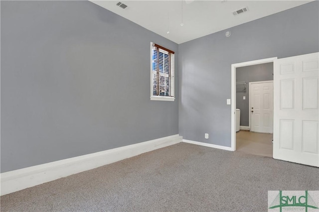 spare room with carpet floors, visible vents, and baseboards