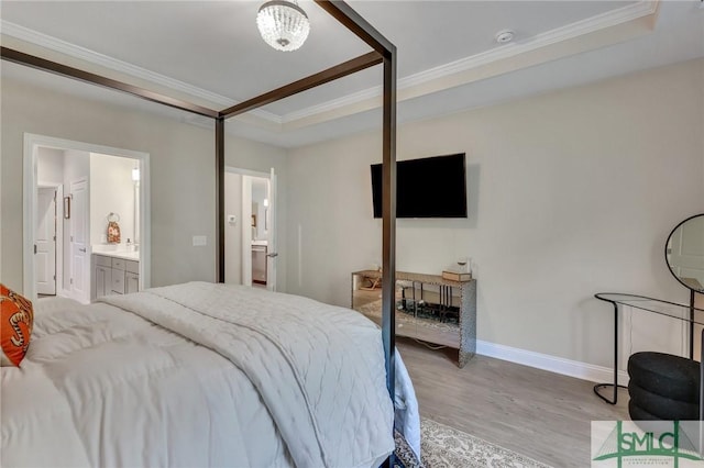 bedroom with ornamental molding, connected bathroom, a raised ceiling, and light wood-type flooring