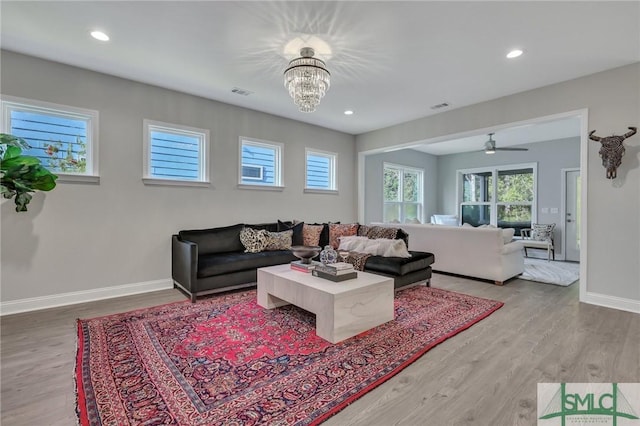 living room featuring wood-type flooring and ceiling fan with notable chandelier