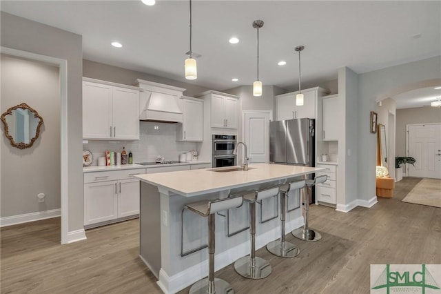 kitchen featuring white cabinetry, custom range hood, and a center island with sink