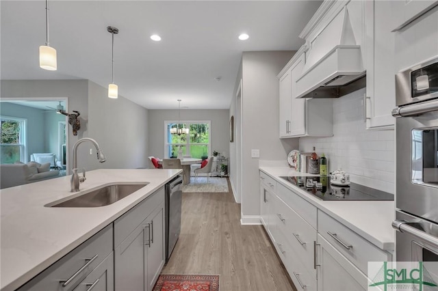 kitchen with premium range hood, sink, black electric cooktop, pendant lighting, and white cabinets