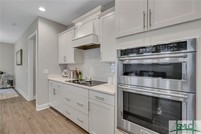 kitchen featuring white cabinetry, double oven, tasteful backsplash, black electric stovetop, and custom exhaust hood