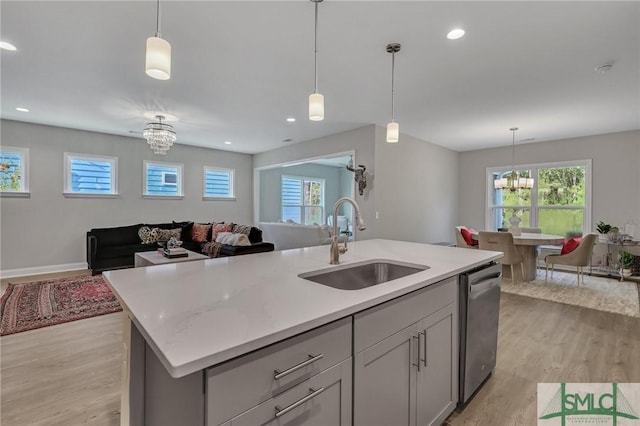 kitchen featuring sink, gray cabinetry, dishwasher, a notable chandelier, and a kitchen island with sink