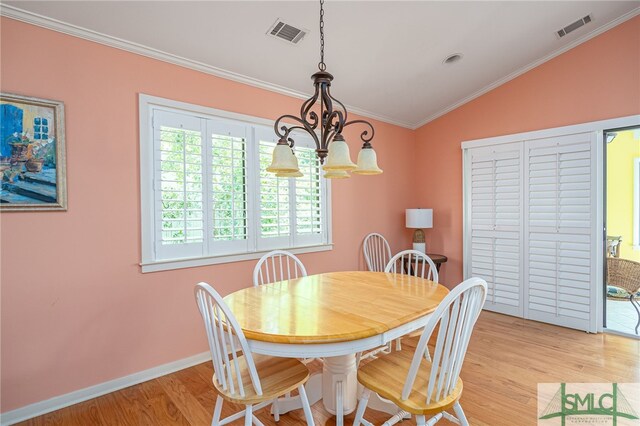 dining space with ornamental molding, lofted ceiling, a chandelier, and light hardwood / wood-style flooring