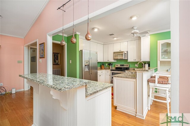 kitchen featuring light hardwood / wood-style floors, a breakfast bar area, white cabinets, kitchen peninsula, and stainless steel appliances