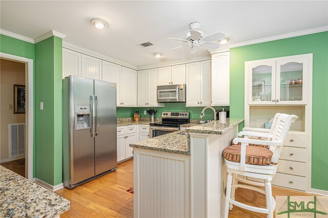 kitchen featuring stainless steel appliances, white cabinets, and kitchen peninsula