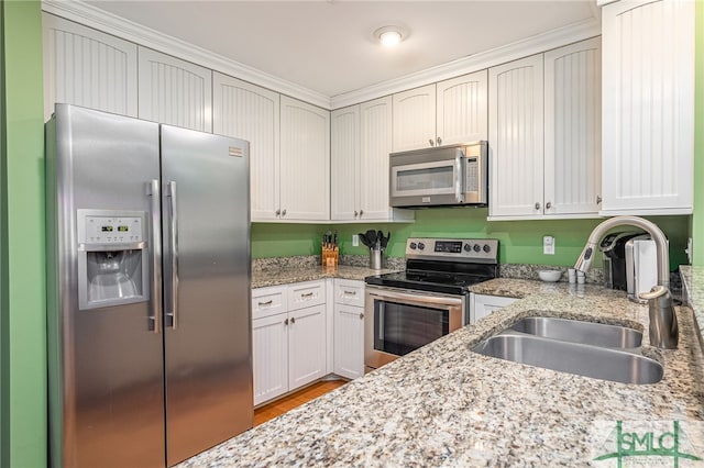 kitchen featuring light stone countertops, white cabinets, appliances with stainless steel finishes, and sink