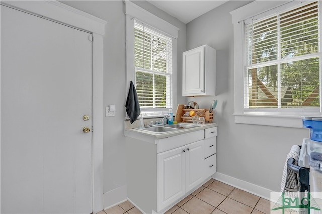 clothes washing area with sink, plenty of natural light, and light tile patterned floors