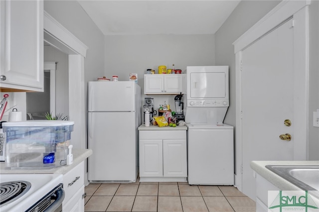 kitchen with white cabinets, stacked washer and dryer, white refrigerator, and light tile patterned floors