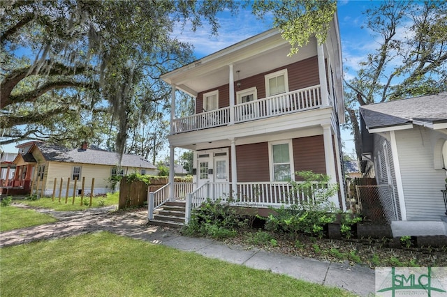 view of front facade with a balcony, a porch, and a front yard