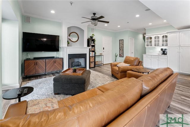 living room featuring ceiling fan, crown molding, and light hardwood / wood-style floors