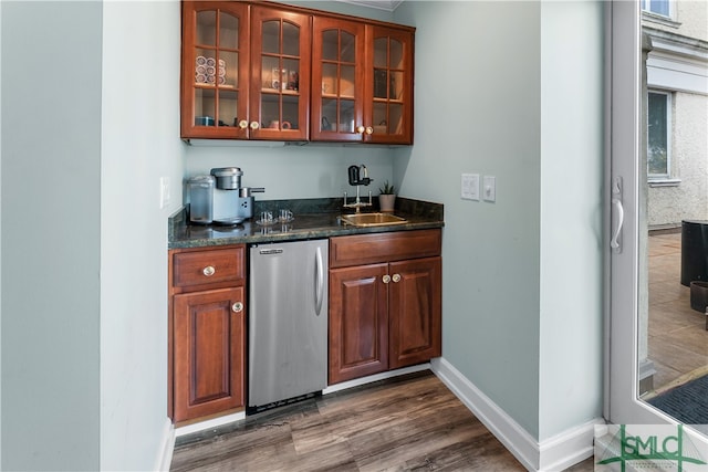 bar with dark stone countertops, sink, dark hardwood / wood-style floors, and stainless steel fridge