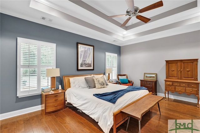 bedroom featuring hardwood / wood-style flooring, ceiling fan, and a raised ceiling