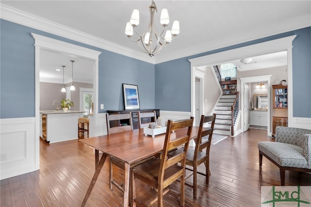 dining room with dark wood-type flooring, ornamental molding, a chandelier, and sink