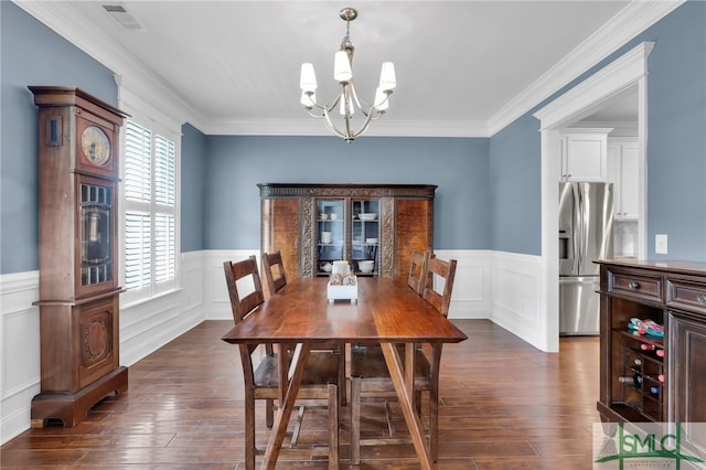 dining area featuring dark wood-type flooring, crown molding, and a notable chandelier