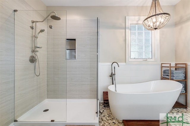 bathroom with shower with separate bathtub, tile walls, and a chandelier