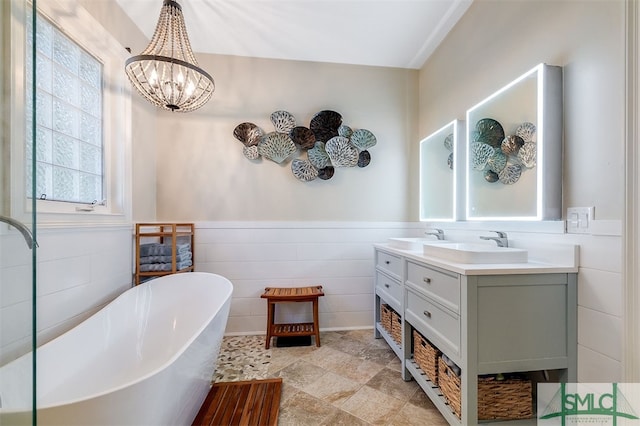 bathroom with tile walls, vanity, a tub, and a chandelier