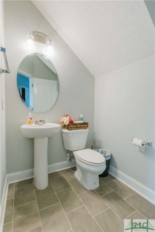 bathroom with vaulted ceiling, a textured ceiling, and toilet