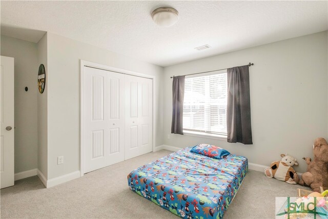 carpeted bedroom featuring a textured ceiling and a closet