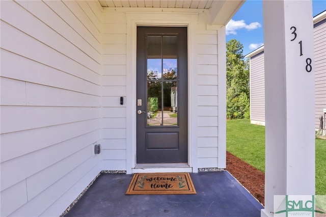 view of exterior entry featuring a lawn