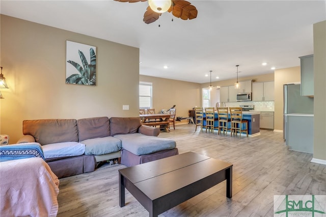 living room with light wood-type flooring and ceiling fan